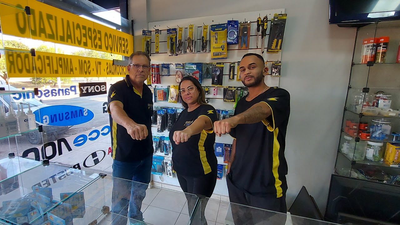 Equipe da Hosken Eletrônica no balcão da loja, com o uniforme preto e amarelo